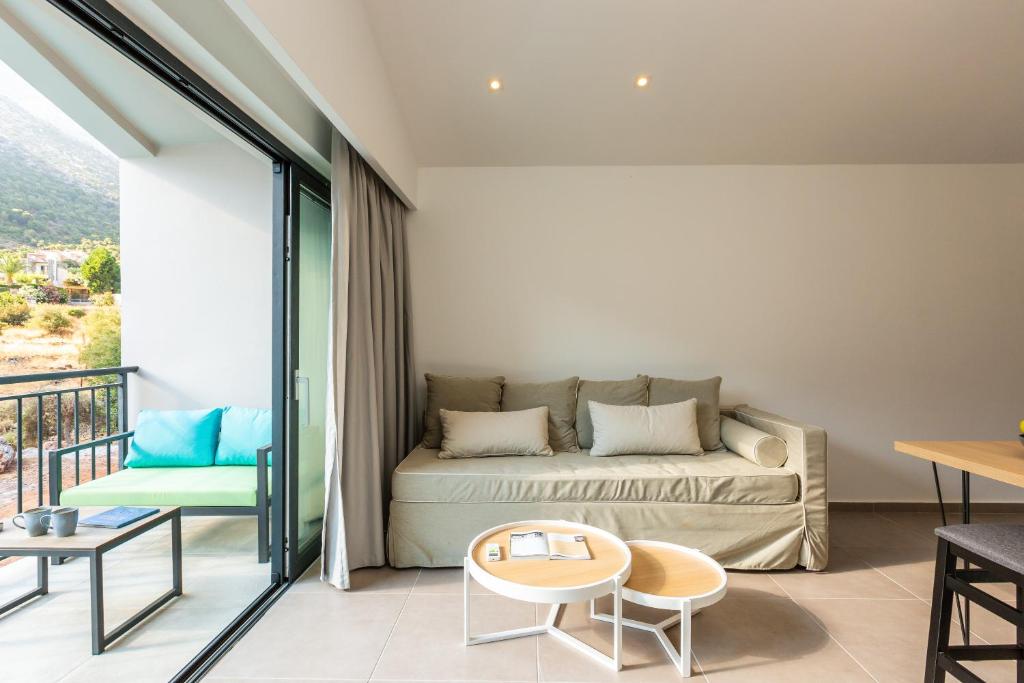 Mūsdienīgs viesnīcas numurs ar gaišu interjeru, kurā ir dīvāns, ēdamgaldiņš un piekļuve balkoniem ar skatu uz dabu. Ideāli piemērots relaksācijai un atpūtai.