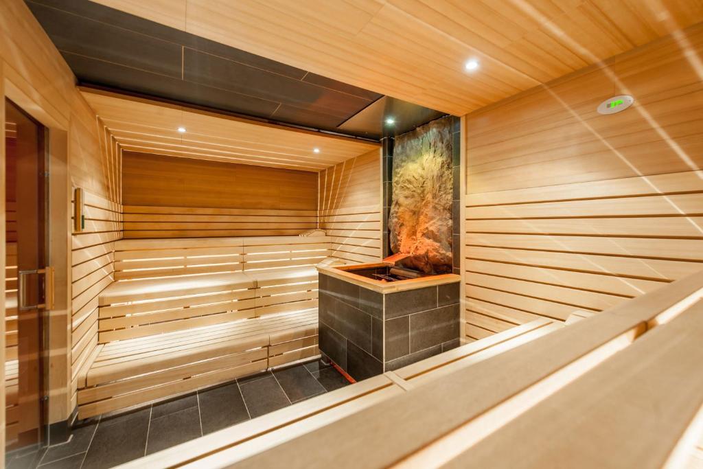 Mūsdienīga sauna ar koka apdari un akmens kamīnu, piedāvājot relaksējošu atmosfēru un siltumu. Ideāla vieta atpūtai un stresa mazināšanai.