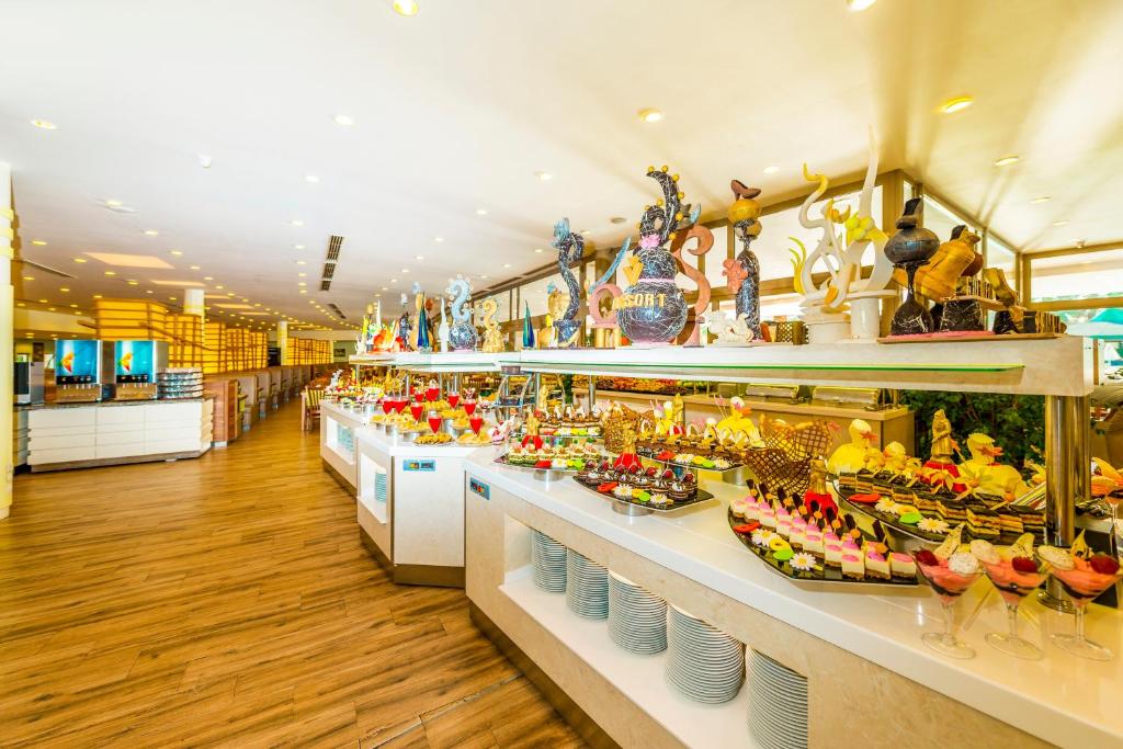 Bufete ar plašu desertu klāstu, ieskaitot krāsainus kūkas un saldējumus, kas izkārtoti uz elegantām plauktiem. Restorāna interjers ir gaišs un moderns, radot patīkamu atmosfēru.