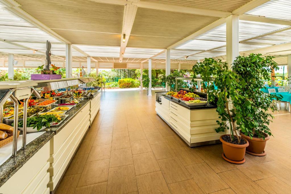 Plaša bufete ar dažādiem dārzeņiem un augļiem, apgaismotā telpā ar zaļajiem augiem un mierīgu atmosfēru.