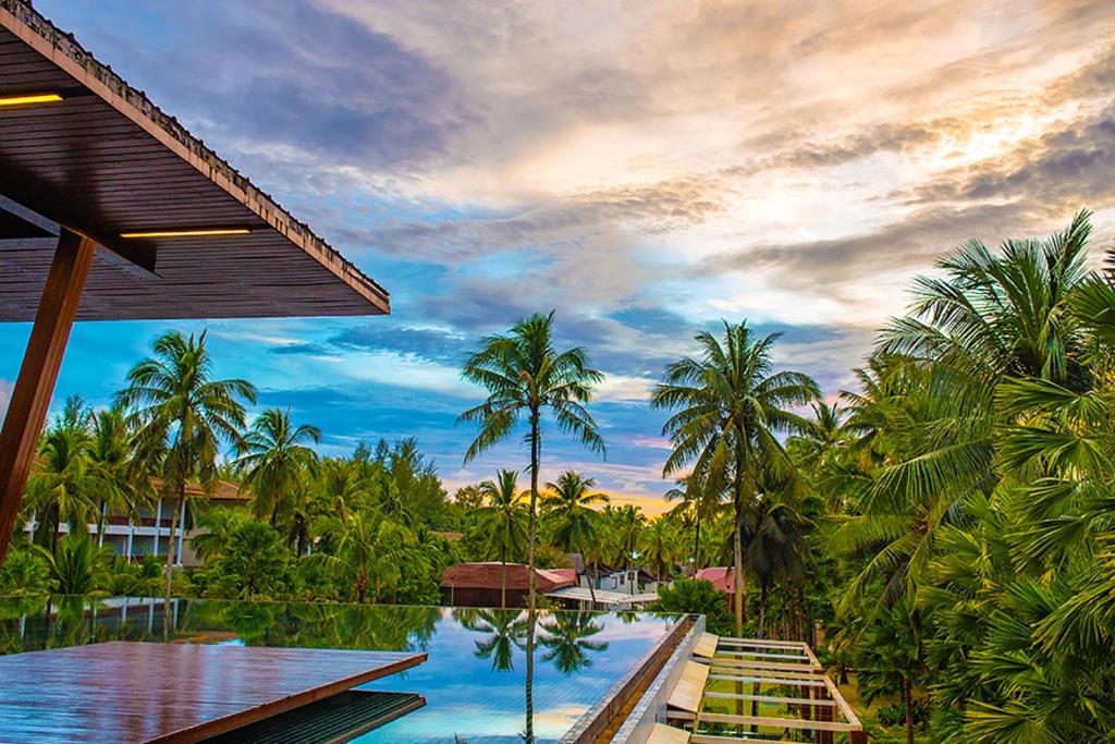 Graceland Khaolak Resort & Spa skats uz baseinu un palmu dārzu piekrastē.