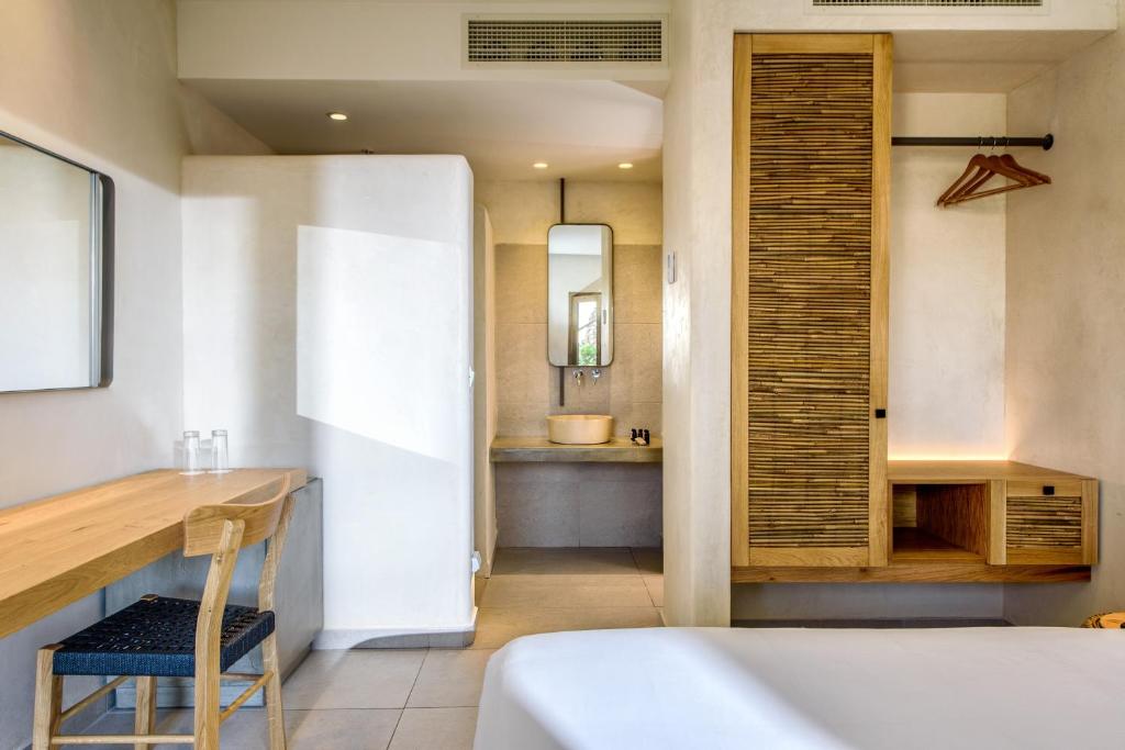 Mūsdienīgs viesnīcas numurs ar koka mēbelēm, iekārtotu rakstāmgaldu un vannas istabu. Gaismas toņi un vienkārša dizaina elementi rada relaksējošu atmosfēru.