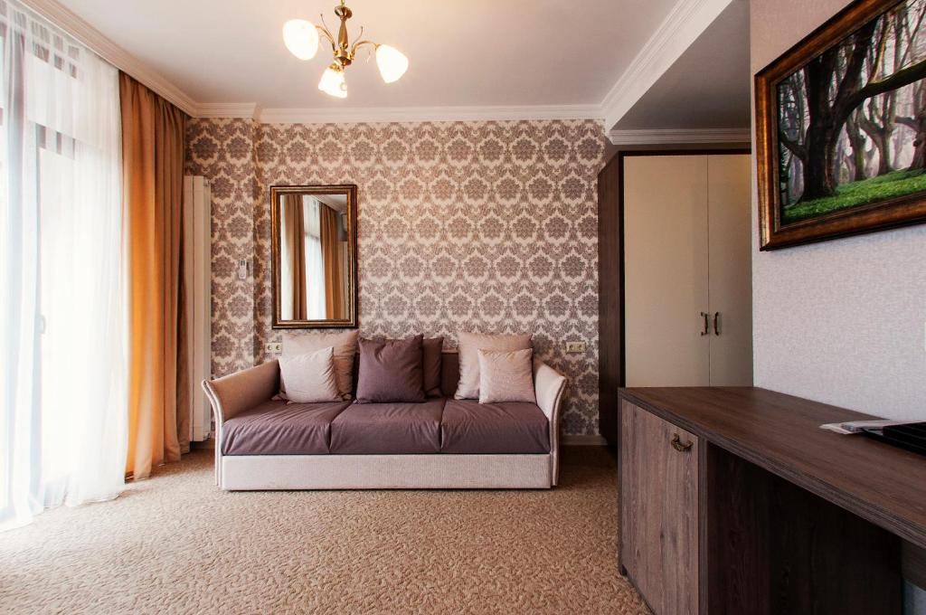 Mūsdienīga viesistaba ar elegantu tapeti, dīvānu un spoguli, kas rada siltu un viesmīlīgu atmosfēru. Interjeru papildina glezna un dabīgā apgaismojuma elements.