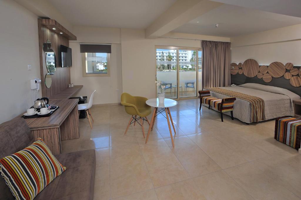 Mūsdienīgs viesnīcas numurs ar plašu telpu, ērtu dīvānu, galdu un gultu, kā arī lieliem logiem, caur kuriem ieplūst dabiska gaisma.