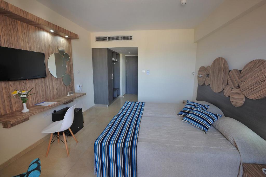 Moderns viesnīcas numurs ar divguļamo gultu, televizoru un dekoratīviem elementiem. Telpa ir gaiša un eleganta, ar funkcionāliem mēbeļu risinājumiem.