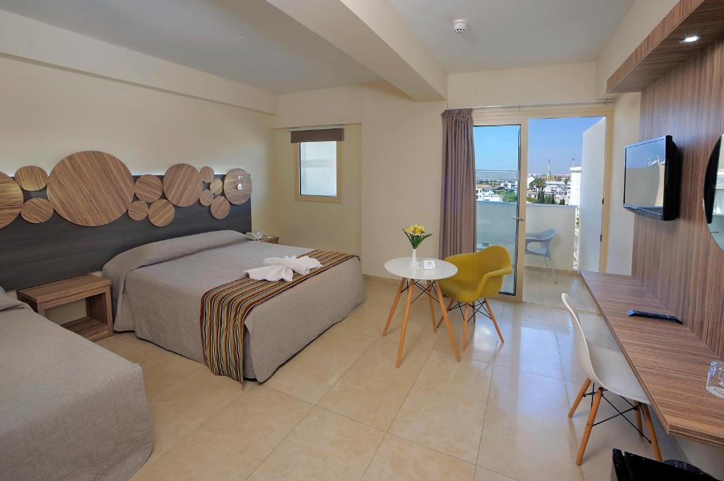 Mūsdienīga viesnīcas numuriņa interjers ar divām gultām, koka dekoratīviem elementiem un balkonu. Numuriņā ir arī televizors un galdiņš ar krēsliem.