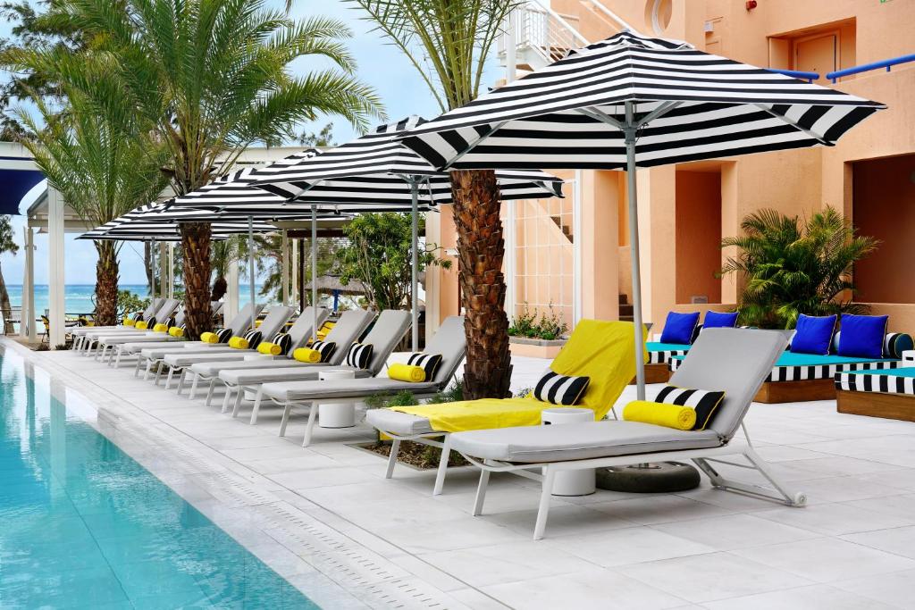 Atpūtas zona pie baseina viesnīcā SALT of Palmar ar šūpuļkrēsliem un sauļošanās krēsliem.