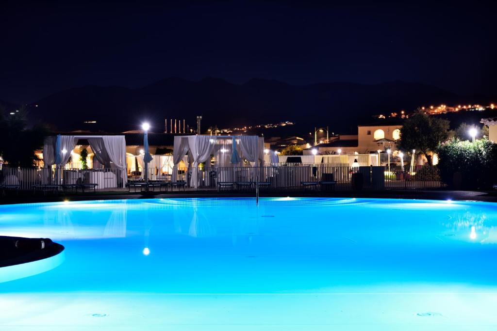 Janna 'e Sole Resort izgaismots peldbaseins naktī ar atpūtas zonu un kalniem fonā