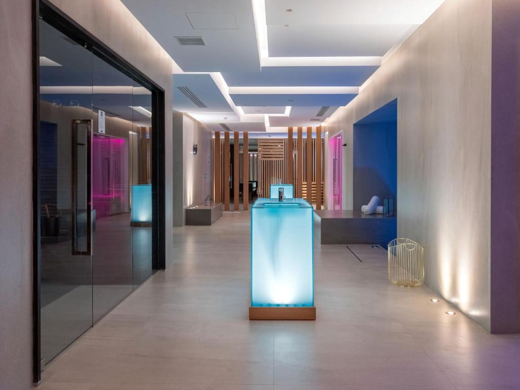 Mūsdienīga viesnīcas recepcija ar spilgtām gaismām un minimālistisku dizainu, radot relaksējošu atmosfēru. Stikla galds ar apgaismojumu pievērš uzmanību un aicina viesus.