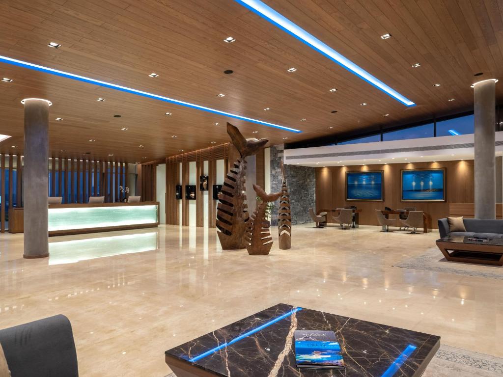 Mūsdienīgs viesnīcas reģistratūras interjers ar koka un akmens elementiem, izceļot māksliniecisku skulptūru un elegantus gaismas risinājumus.