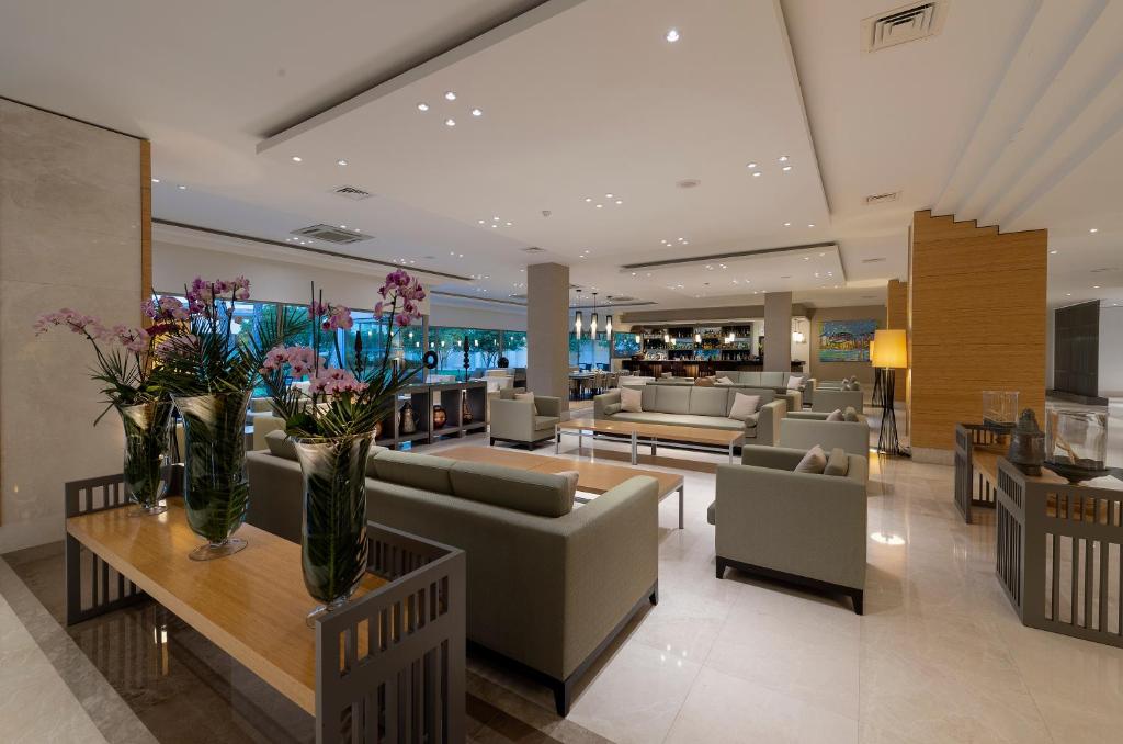 Mūsdienīgs viesnīcas Turquoise Hotel vestibils ar elegantiem dīvāniem un ziediem.