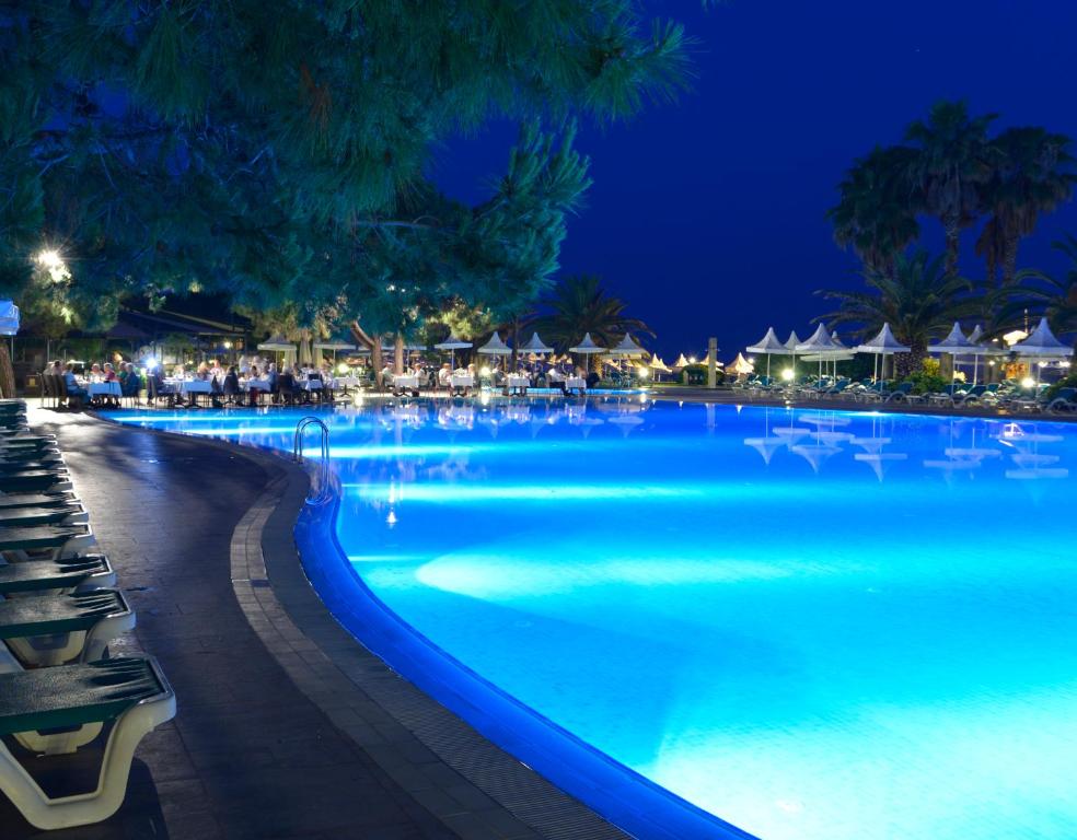 Gaismas pie Turquoise Hotel baseina piekrastē naktī.