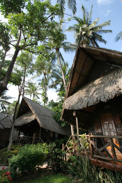 Tropu mājiņas piekrastē Banpu Koh Chang ar zaļiem kokiem un ziediem.