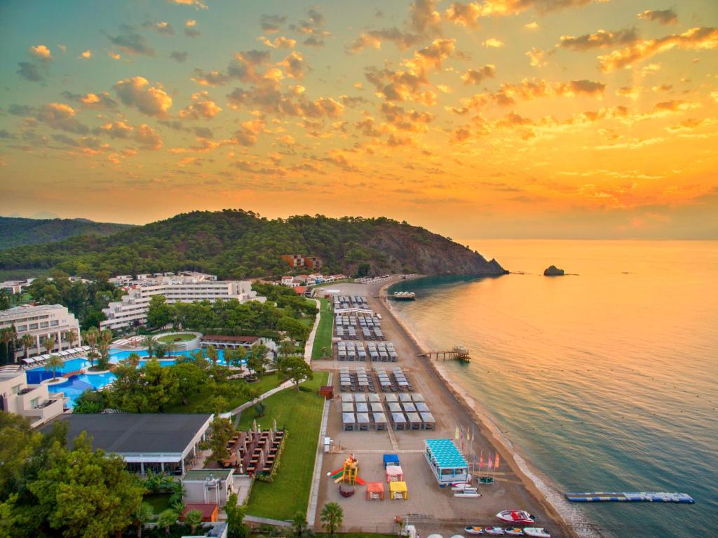 Rixos Premium Tekirova piekrastes skats ar saulrietu un pludmales aktivitātēm.