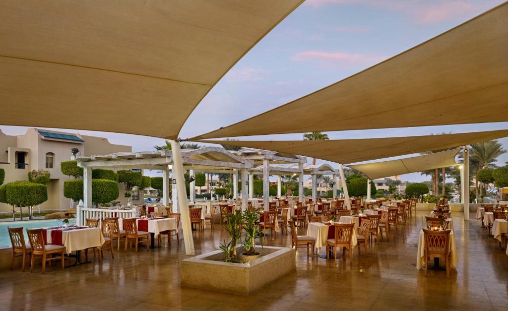 Āra restorāns Coral Sea Holiday Village Resort ar elegantām galdiem un ērtām krēsliem.