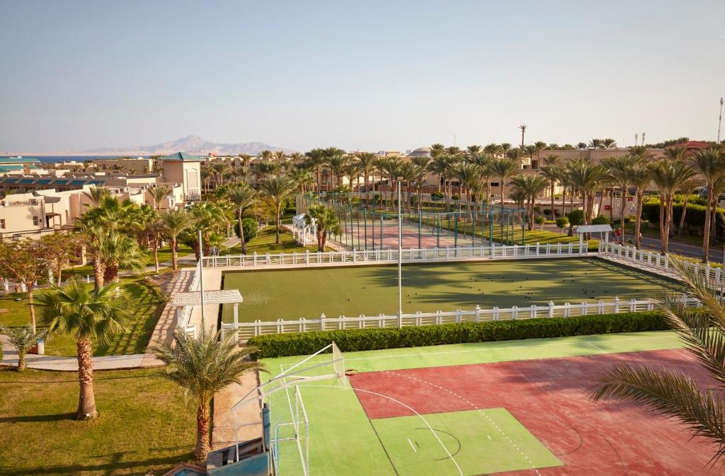 Sporta laukumi Coral Sea Holiday Village Resort piekrastē, palmām un kalniem fona.