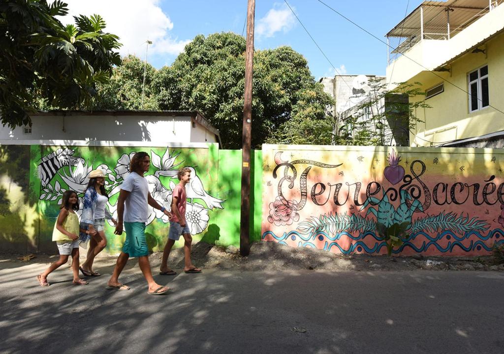 Ģimene pastaigā gar krāsainu mākslas sienu Veranda Tamarin Hotel & Spa.
