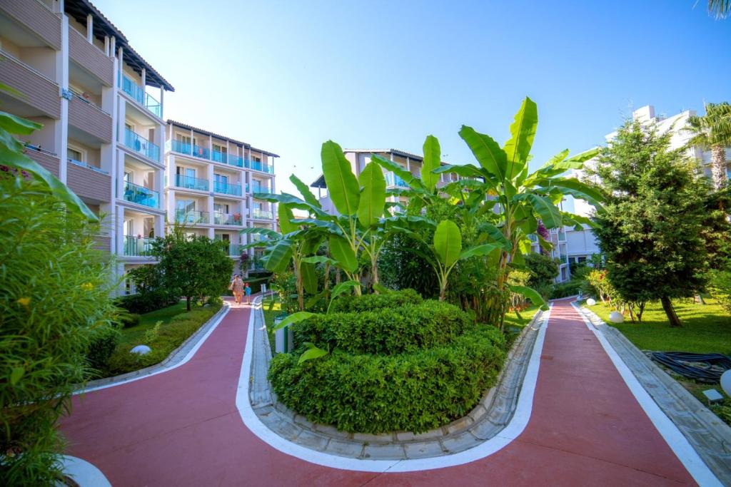 Zaļš dārzs pie Sealife Buket Resort & Beach ar takām un viesnīcas ēkām.