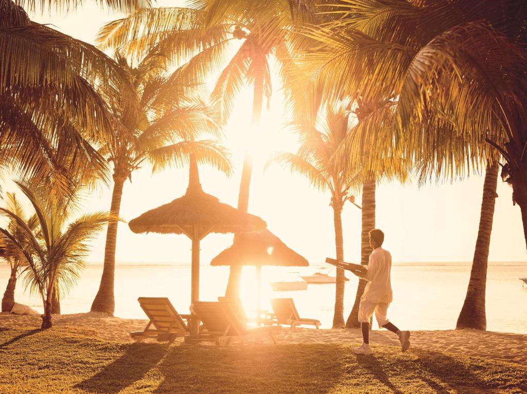 Saulaina pludmale pie LUX* Le Morne ar palmu kokiem un sauļošanās krēsliem