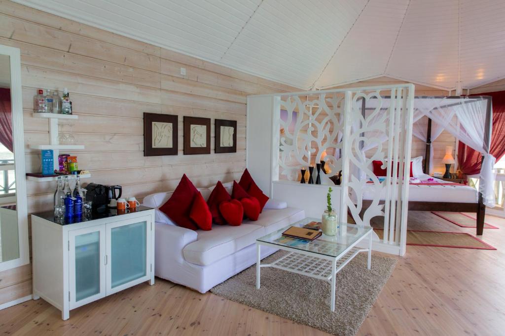 Mūsdienīgs viesnīcas numurs ar elegantiem sarkaniem spilveniem, stilīgu baltu dīvānu un atsevišķu guļamistabas zonu. Telpas interjers ir gaišs un gaisīgs, radot relaksējošu atmosfēru.