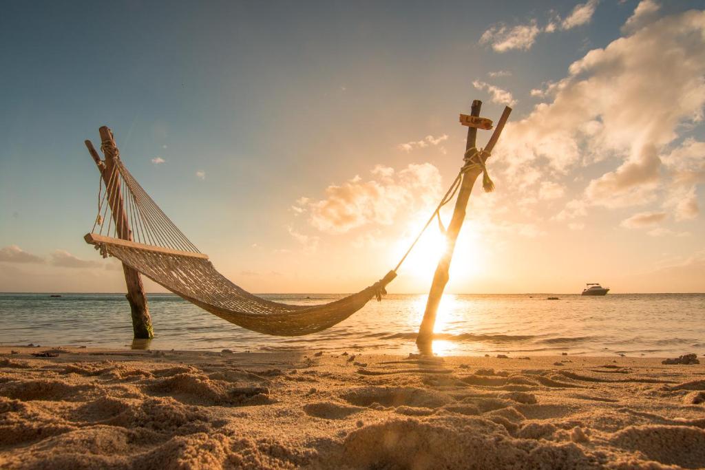 A hammock by the beach at LUX* Le Morne during sunset.