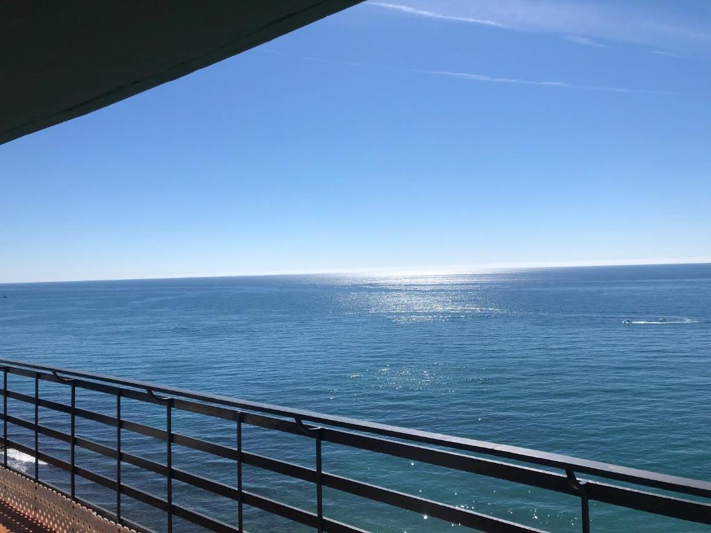 Skats uz mierīgu jūru ar skaistu debesu zilu, no balkona. Ūdens virsma spīd saules gaismā.