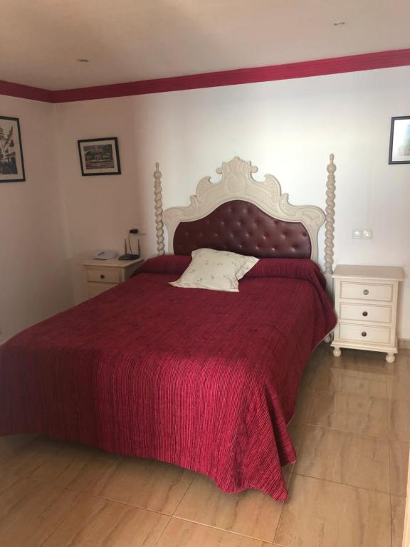 Gultas telpa ar sarkanu segumu, elegantu gultas galvu un naktsgaldiem. Interjerā ir attēli uz sienām, radot mājīgu atmosfēru.