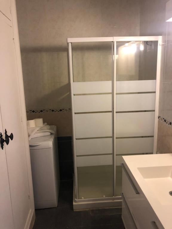 Mūsdienīgs vannas istabas interjers ar dušas kabīni, veļas mašīnu un izlietni. Telpa ir gaiša un funkcionāla, ar neitrālām krāsām un moderniem elementiem.