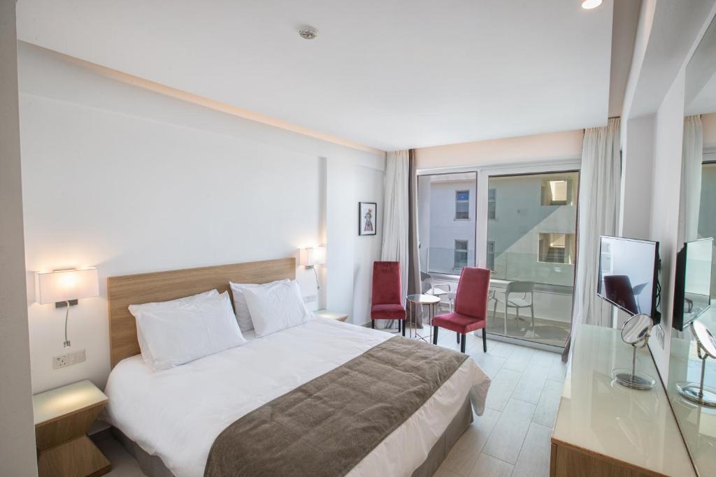 Mūsdienīgs viesnīcas numurs ar divguļamo gultu, sarkaniem krēsliem un privātu balkonu. Izsmalcināta interjera dizains un liela loga zona nodrošina dabīgu apgaismojumu.