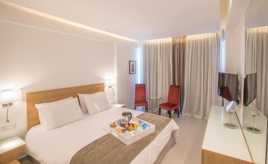 Mūsdienīgs viesnīcas numurs ar divguļamo gultu, vienkāršu dizainu un ērtu mēbelējumu. Uz galda atrodas augļu un dzērienu pasniegšanas tray.