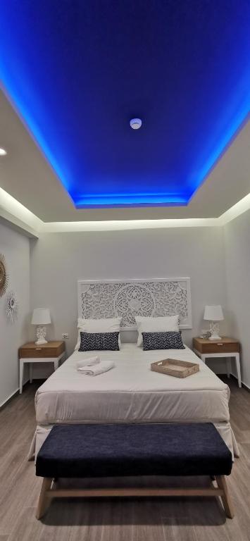 Moderns guļamistabas interjers ar zilu LED apgaismojumu un elegantu gultu. Telpā ir gaismas, koka grīda un dekoratīvi elementi, kas rada mierīgu atmosfēru.