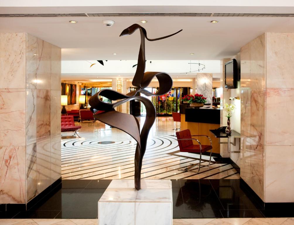Mūsdienīga bronzas skulptūra rotā viesnīcas vestibiļu, veidojot elegantu un māksliniecisku atmosfēru. Skulptūra ir izvietota uz marmora pamatnes, kas papildina interjera izsmalcinātību.
