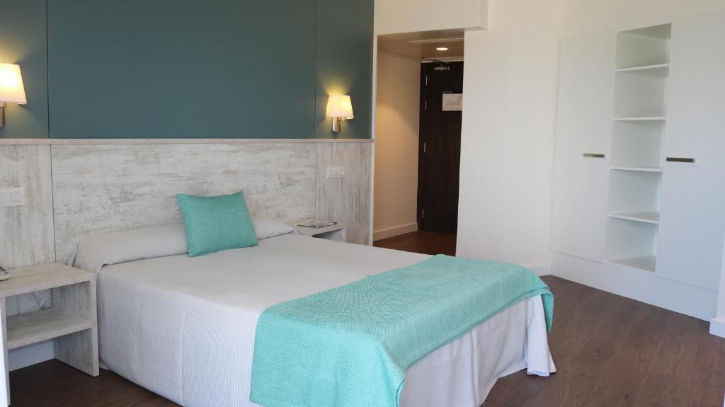 Moderns guļamistabas interjers ar gultu, spilveniem un dekoratīvu segumu. Telpa ir gaiša un eleganta, ar mierīgu krāsu paleti un koka grīdu.