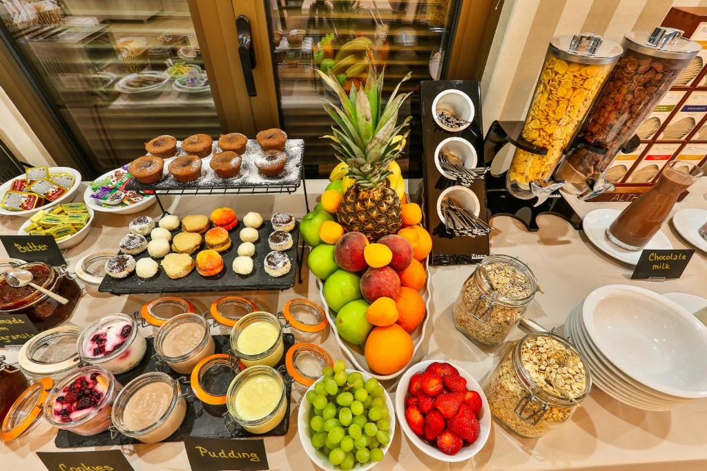 Bagātīgs brokastu bufete ar dažādiem desertiem, augļiem un graudaugiem, tostarp kūkām, pudiņiem un šokolādes pienu. Ideāli piemērots gardēžiem, kas meklē dažādus našķus.