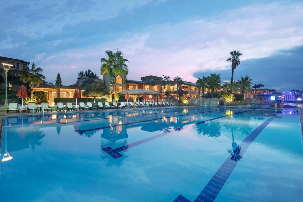 Pine Beach Belek baseins ar palmām un saulessargiem piekrastē