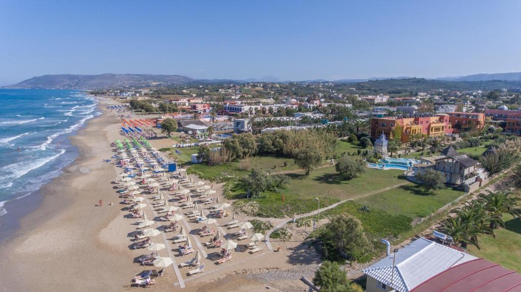 Pludmale ar saulessargiem un sauļošanās krēsliem, skats uz jūru un tuvumā esošajām ēkām. Ideāla vieta atpūtai pie jūras.