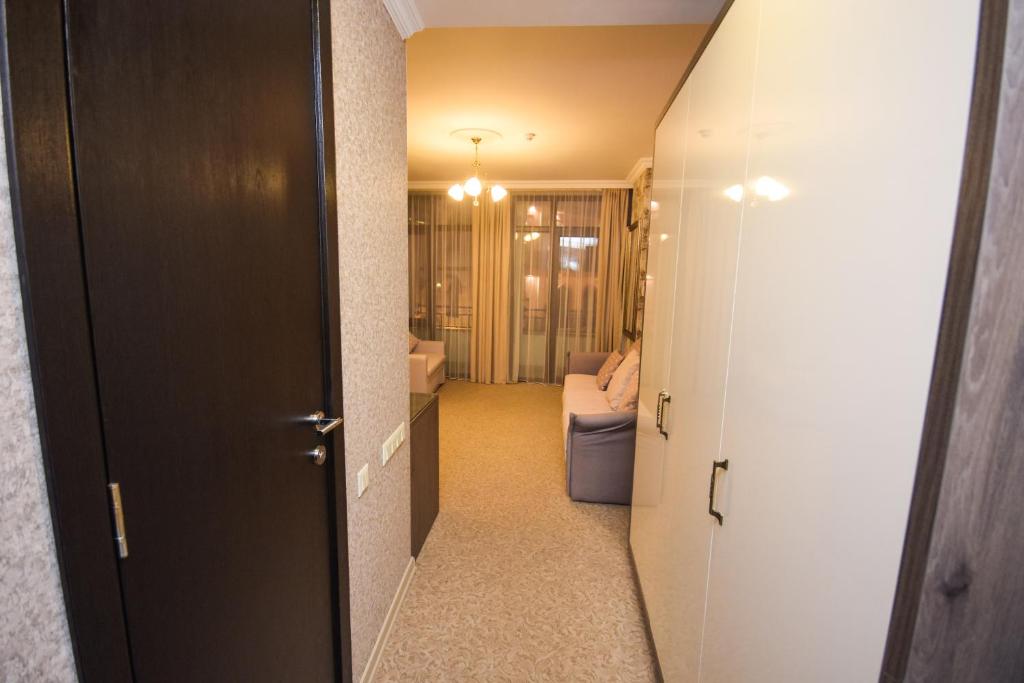 Mūsdienīgs un gaišs koridors ar tumšu durvju un skapju dizainu, kas ved uz viesistabu ar dīvānu un logiem ar aizkariem.