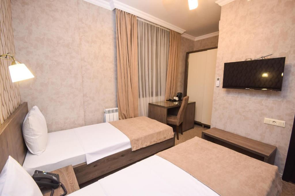 Mūsdienīga viesnīcas numura iekārtojums ar divām atsevišķām gultām, darba galdu un televizoru. Interjers ir neitrālos toņos ar dabīgu apgaismojumu.