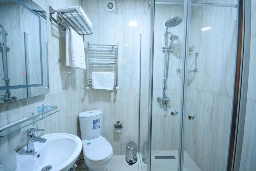 Mūsdienīga vannas istaba ar stikla dušu, tualeti un izsmalcinātu iekārtojumu. Svaigi dvieļi un higiēnas piederumi pieejami uz plaukta.