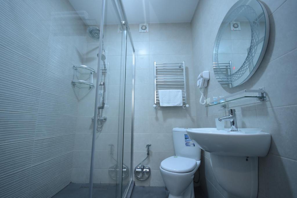 Mūsdienīga vannas istaba ar stikla dušu, baltu izlietni un higiēnas piederumiem. Interjers ir gaišs un elegants, radot skaidru un tīru atmosfēru.