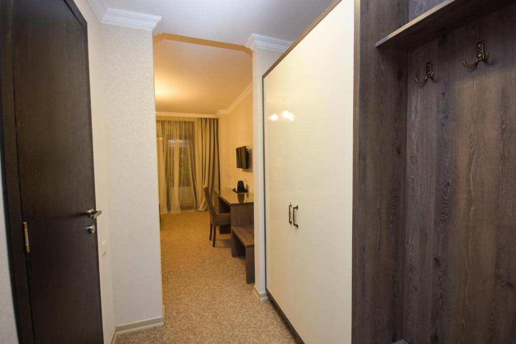 Korektā moderna viesnīcas istabas ieeja ar drēbju skapjiem un darba galdu. Gaismas un neitrālas krāsas rada patīkamu atmosfēru.