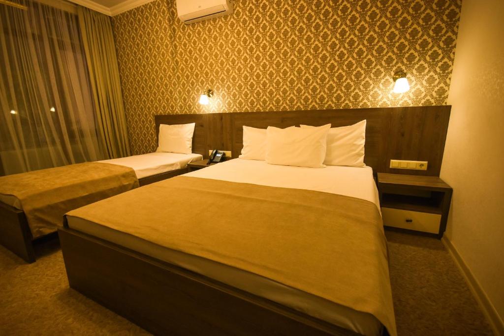 Mūsdienīgs viesnīcas numurs ar divām gultām, elegantām gultas veļām un patīkamu apgaismojumu. Sienas rotā stilīga tapete, radot siltu un viesmīlīgu atmosfēru.