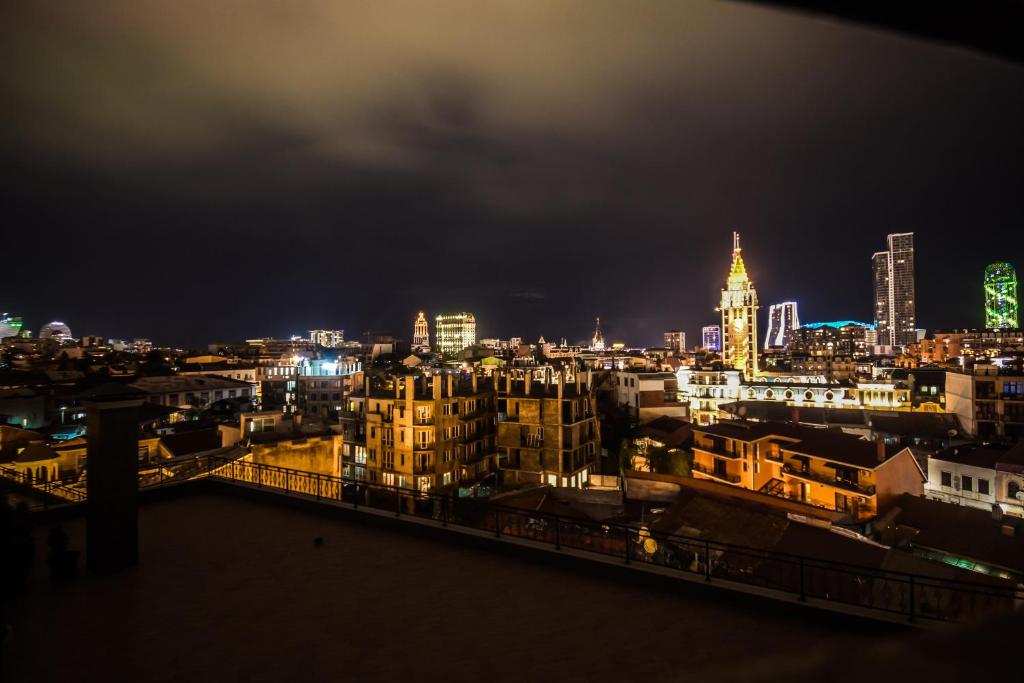 Pilsētas ainava naktī ar apgaismotām ēkām un debesskrāpjiem, izceļot arhitektūras daudzveidību un noskaņu.