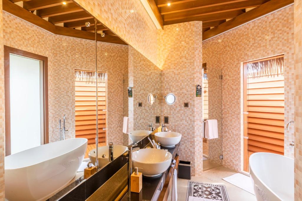 Mūsdienīgs vannasistabas interjers ar elegantu vannu un divām izlietnēm, izciliem apgaismojumiem un dabīgiem materiāliem. Gaismas un telpas plānojums rada relaksējošu atmosfēru.