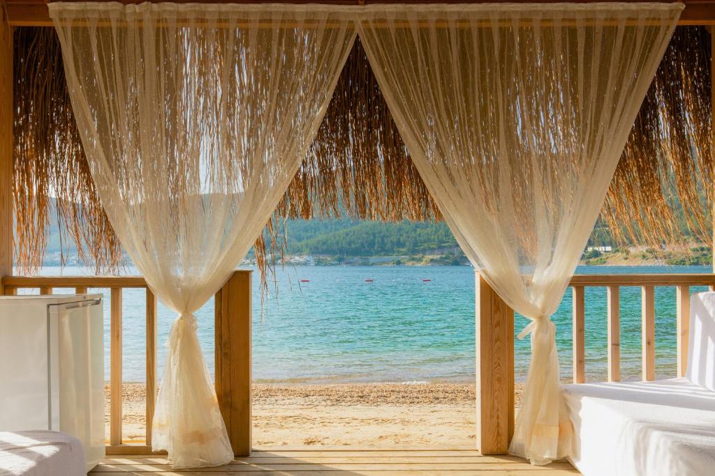 Skats uz pludmali no La Blanche Island Bodrum, caur caurspīdīgiem aizkariem.