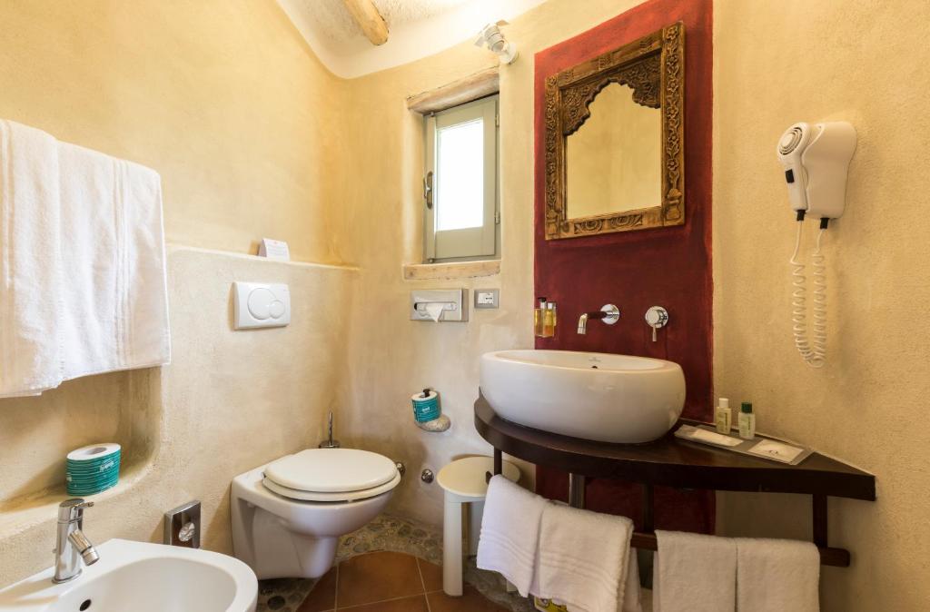 Mūsdienīgs vannas istabas interjers ar elegantu izskatu, iekļaujot apaļu izlietni un dekoratīvu spoguli uz sarkanā fona. Gaismas krāsas sienas un atvērta loga dizains rada gaišu un patīkamu atmosfēru.