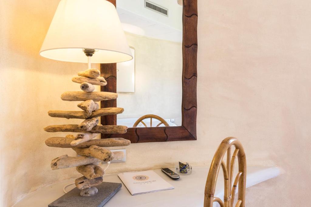 Mūsdienīgs galda lampa, kas izgatavota no koka gabaliem, atrodas uz darba virsmas blakus spogulim un koka krēslam, radot siltu un viesmīlīgu atmosfēru.