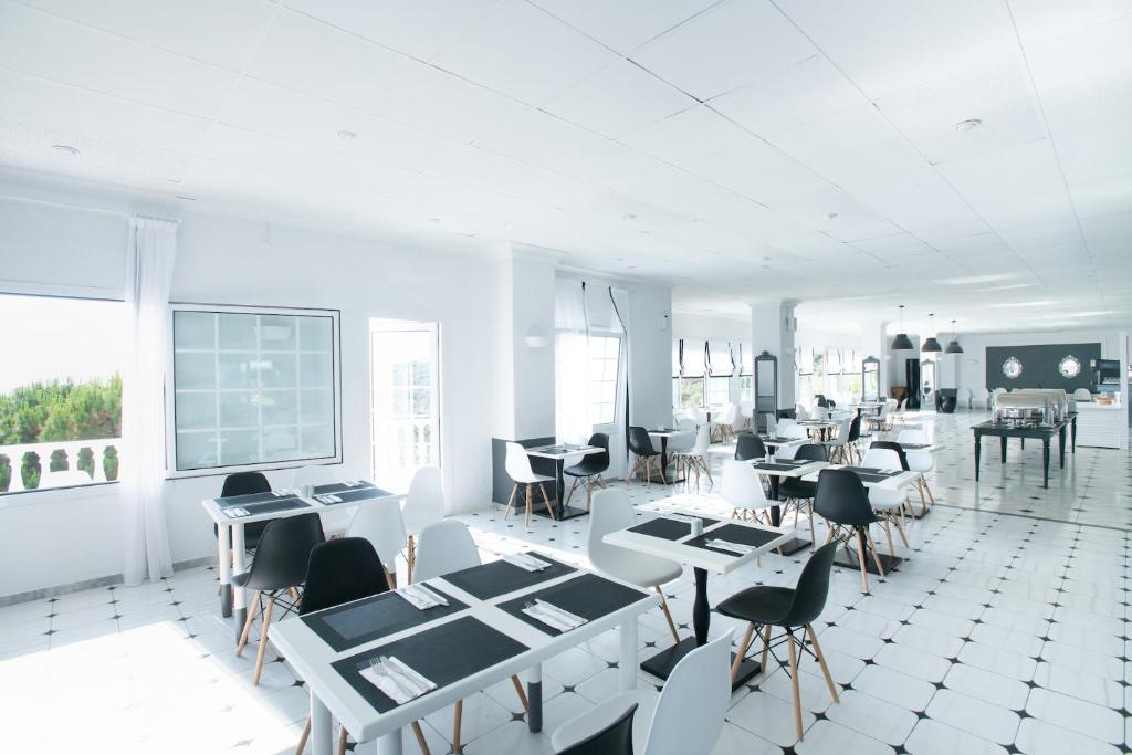 Mūsdienīga restorāna iekšējā telpa ar baltām sienām un melnām un baltām mēbelēm. Labi apgaismots un plašs, ar lieliem logiem, kas piedāvā gleznainu skatu.