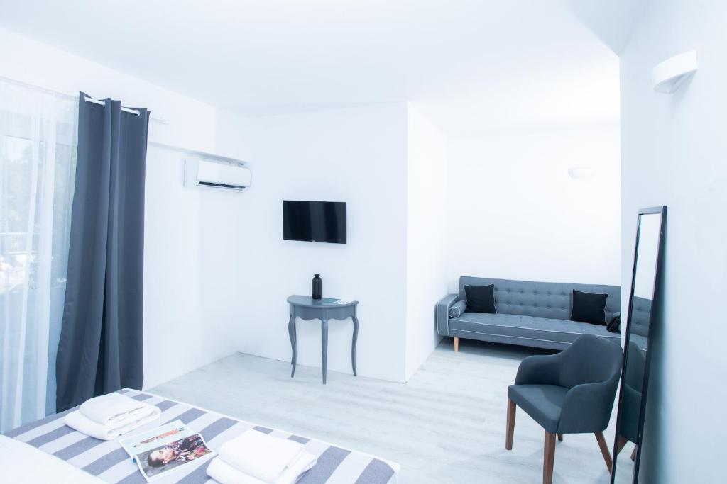 Moderns viesnīcas numurs ar gaišām sienām, ērtu dīvānu un televizoru. Interjerā ir minimālistisks dizains ar elegantiem aksesuāriem.