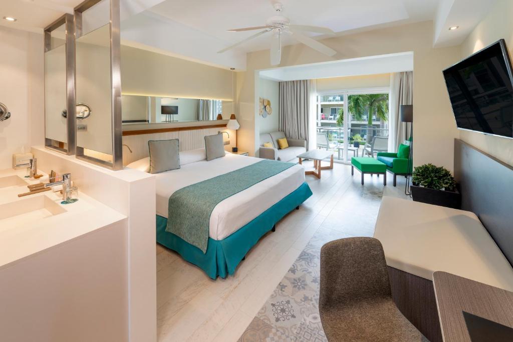 Mūsdienīga viesnīcas numura iekārtojums ar plašu gultu, modernām mēbelēm un lieliem logiem, kas nodrošina dabisko apgaismojumu. Numurā ir arī ērti sēdvietas un vannas istaba ar divām izlietnēm.